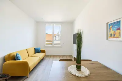 a living room with a yellow couch and a table at LE LOGIS CANNOIS au calme en centre-ville in Cannes