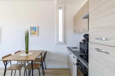 a kitchen with a wooden table and a dining room at LE LOGIS CANNOIS au calme en centre-ville in Cannes