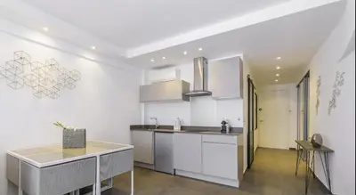 a kitchen with white cabinets and a table at Superbe T2 lumineux dans le centre CIO1899 in Cannes