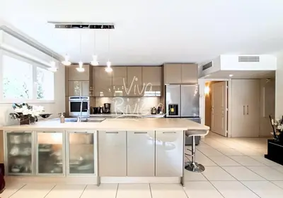 a kitchen with white cabinets and a large island at Viva Riviera -14 Avenue Isola Bella in Cannes