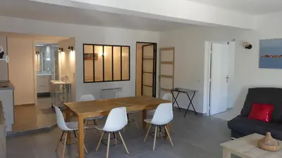 a living room with a wooden table and white chairs at Bas de villa prestations haut de gamme in Vallauris