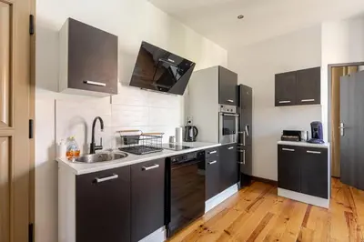 a kitchen with black and white appliances and wooden floors at Cannes, charmant 3 pièces proche centre et plages in Cannes