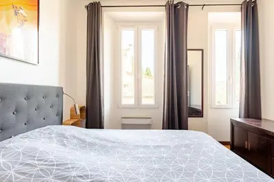 a bedroom with a large bed and two windows at Cannes, charmant 3 pièces proche centre et plages in Cannes