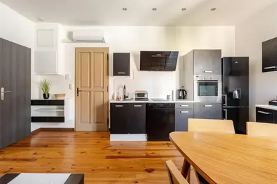 a kitchen with black and white appliances and a wooden table at Cannes, charmant 3 pièces proche centre et plages in Cannes
