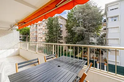 a balcony with a wooden table and chairs on it at CANNES 2 P avec terrasse PROCHE Hôtel Martinez in Cannes