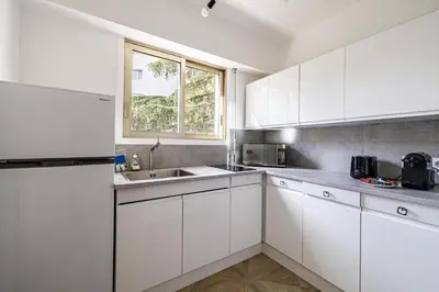 a white kitchen with white cabinets and a window at CANNES 2 P avec terrasse PROCHE Hôtel Martinez in Cannes