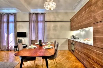 a dining room with a wooden table and a kitchen at FAR5 - 3 chambres à deux pas de la rue d'Antibes in Cannes