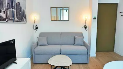 a living room with a blue couch and a tv at Proche Carlton & Croisette, Appartement 303 in Cannes
