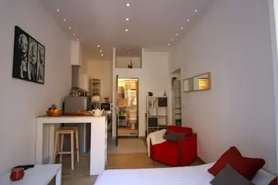 a living room with a red chair and a kitchen at Le Borniol ! Idéal ! Congrès! Central! lumineux! in Cannes