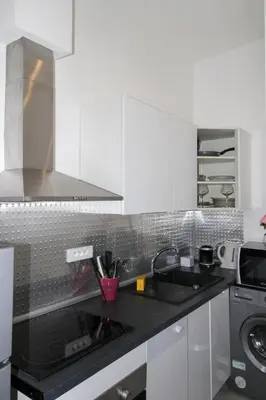 a kitchen with white cabinets and a black counter top at Le Borniol ! Idéal ! Congrès! Central! lumineux! in Cannes