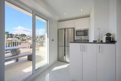 a white kitchen with a view of a balcony at Coco - Spacieux - Luxueux - VCA in Cannes