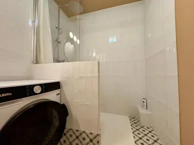a white tiled bathroom with a washing machine in it at Le Montébello By SCLS Locations in Cannes