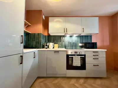 a kitchen with white cabinets and a black appliance at Le Montébello By SCLS Locations in Cannes