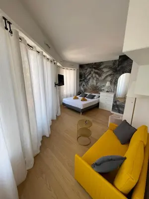 a living room with a yellow couch and a bed at Studio Stella in Cannes