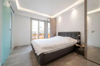 a bedroom with a bed and a large window at REF 1967 - Cannes Center - Apartment for rent in Cannes