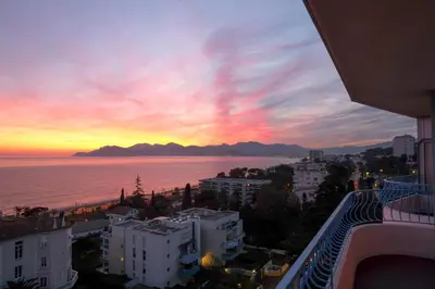 a view of a city with a sunset over the ocean at Western Cannes - Panoramic View in Cannes
