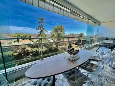 a dining room with a table and chairs and a large window at Grande terrasse vue dégagée mer en Basse Californie in Cannes
