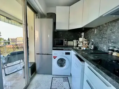 a kitchen with a washing machine and a refrigerator at Grande terrasse vue dégagée mer en Basse Californie in Cannes