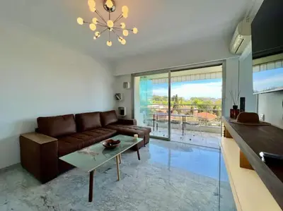 a living room with a brown couch and a table at Grande terrasse vue dégagée mer en Basse Californie in Cannes