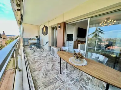 a balcony with a wooden table and chairs on a building at Grande terrasse vue dégagée mer en Basse Californie in Cannes