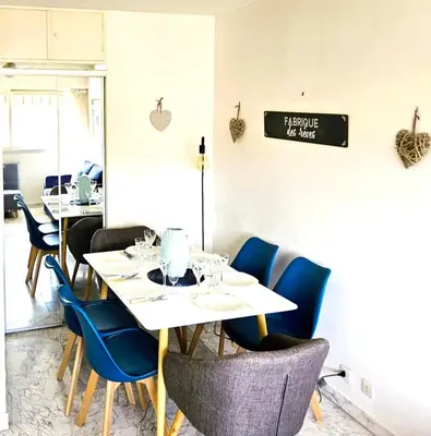 a dining room with white tables and blue chairs at Le 66 Carnot in Cannes