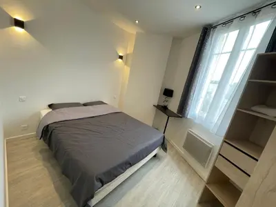 a bedroom with a bed and a large window at 2 pièces au calme in Cannes