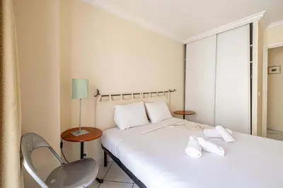 a hotel room with a bed and a chair at LE CASANOVA avec balcon au cœur du centre-ville in Cannes