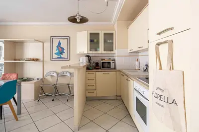 a kitchen with white cabinets and a table and chairs at LE CASANOVA avec balcon au cœur du centre-ville in Cannes