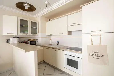 a kitchen with white cabinets and a tote bag at LE CASANOVA avec balcon au cœur du centre-ville in Cannes