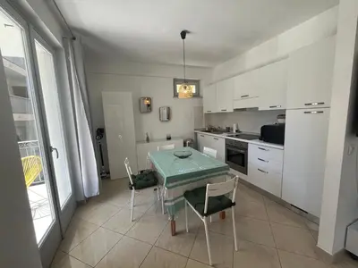 a kitchen with a table and chairs and a kitchen with white cabinets at Nice & Cosy, 4 pers, 1 bedroom with balcony in Cannes