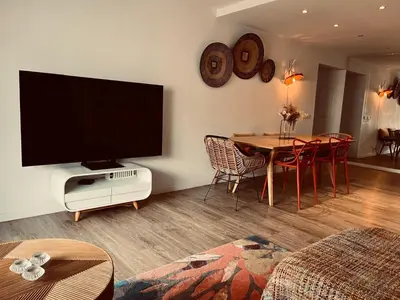 a living room with a television and a table with chairs at T3 pièces lumineux à à 1 min de la plage Quartier Palm Beach Cannes in Cannes