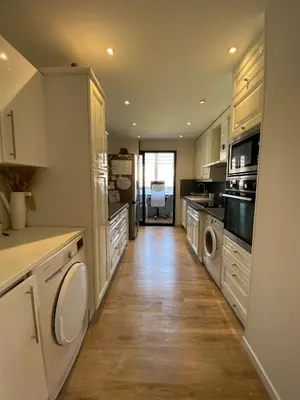 a kitchen with white cabinets and a wooden floor at T3 pièces lumineux à à 1 min de la plage Quartier Palm Beach Cannes in Cannes