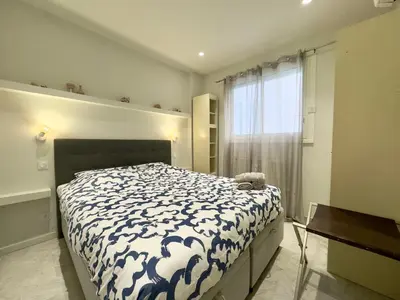 a bedroom with a bed with a blue and white comforter at Le Concorde By SCLS Locations in Cannes