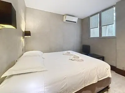 a white bed in a room with a tv at Hoche in Cannes