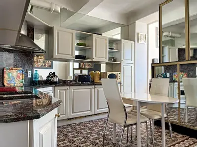 a kitchen with white cabinets and a table and chairs at Studio coeur de Cannes 318L in Cannes