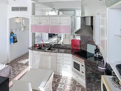 a kitchen with white cabinets and a sink at Studio coeur de Cannes 318L in Cannes