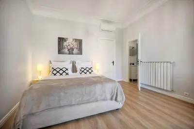 a white bedroom with a large bed and two lamps at SEA PEARL Luxury apartament by the Croisette and the beach in Cannes