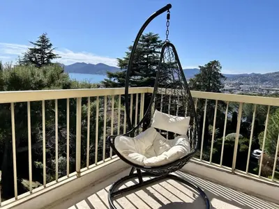 a swinging chair on a balcony with a view at Serenity by the Sea 180 Degrees Sea View and Pool in Cannes