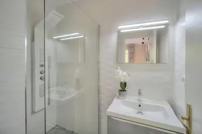 a white bathroom with a sink and a mirror at Serenity by the Sea 180 Degrees Sea View and Pool in Cannes