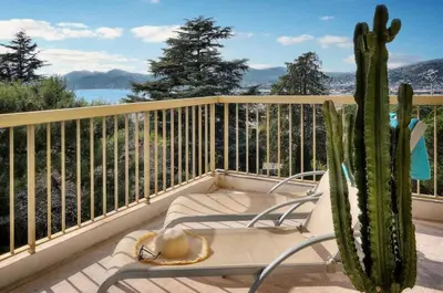 a chair sitting on a balcony with a cactus at Serenity by the Sea 180 Degrees Sea View and Pool in Cannes