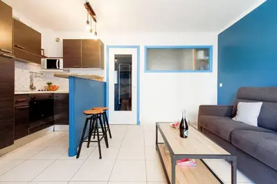 a living room with a couch and a table and a kitchen at Charmant studio près de la mer in Cannes