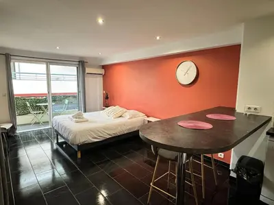 a bedroom with a bed and a table and a clock at Grand Studio Centre Cannes in Cannes