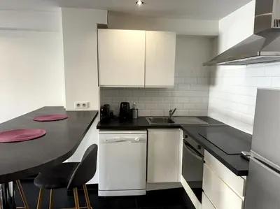 a kitchen with white cabinets and a black counter top at Grand Studio Centre Cannes in Cannes