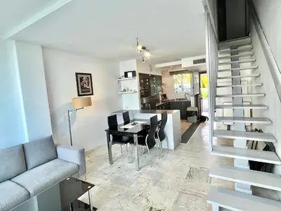 a living room with a staircase and a table and chairs at Château de la mer, by Welcome to Cannes in Cannes