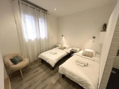 a room with two beds and a chair and a window at Residence Sao Jorge in Cannes