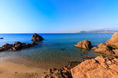 a beach with rocks and the ocean on a clear day at Stunning condo with SEA VIEW Balcony & SWIMMING POOL in Cannes