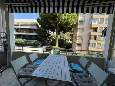 a picnic table and chairs on a balcony with a building at 2P proche mer sib06 in Cannes
