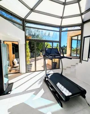 a gym with a treadmill in a room with windows at Ref VCLAIR by Palmes dProperties in Cannes