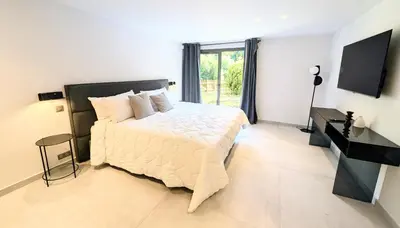 a white bedroom with a bed and a television at Ref VCLAIR by Palmes dProperties in Cannes