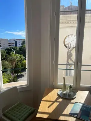 a room with a table and a window with a clock at Cannes Centre Apartment 2-Room by Palais des Festivals & Beach in Cannes